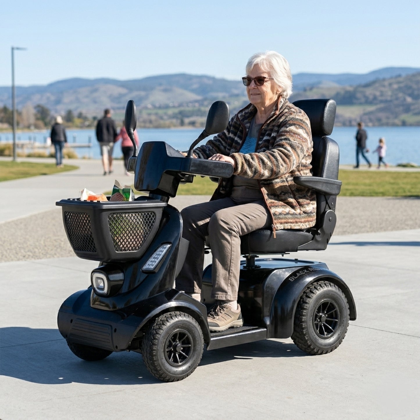 Woman using a mobility scooter by a lake with mountains in the background